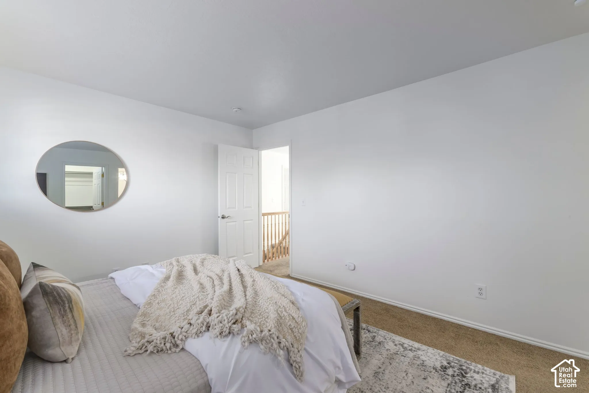 Neutral-toned carpeting, white walls, six-panel interior door, and oval wall-mounted mirror