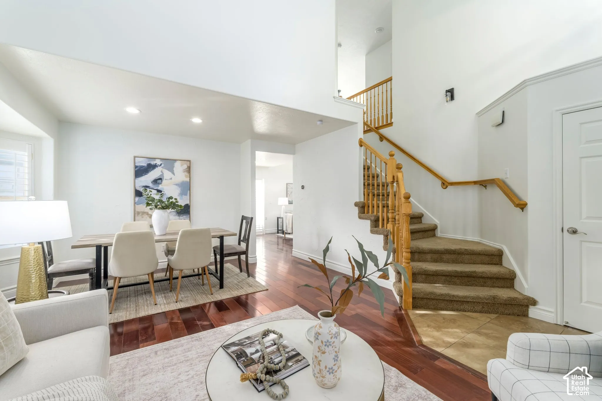 Vaulted ceilings with recessed lighting, dark wood-finish flooring, staircase with natural wood railings, and tile flooring at the entry