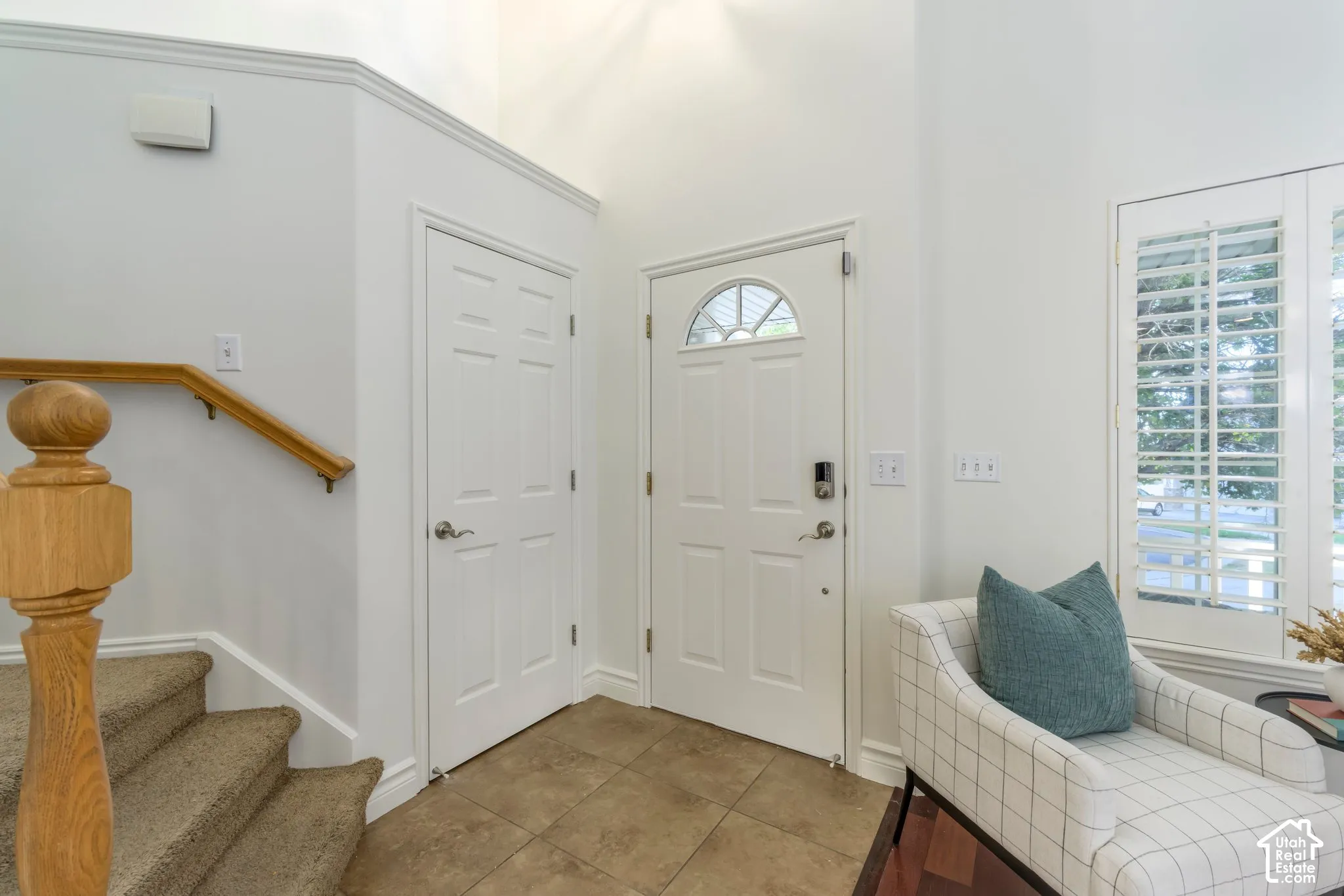 Foyer featuring high ceilings, tile flooring, an entry door with a semi-circular transom window, and a staircase with a wooden handrail and turned baluster