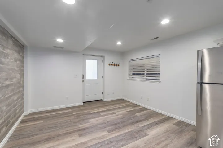 Interior space featuring wood-finish flooring, a wood-plank accent wall, recessed lighting, and a window with horizontal blinds