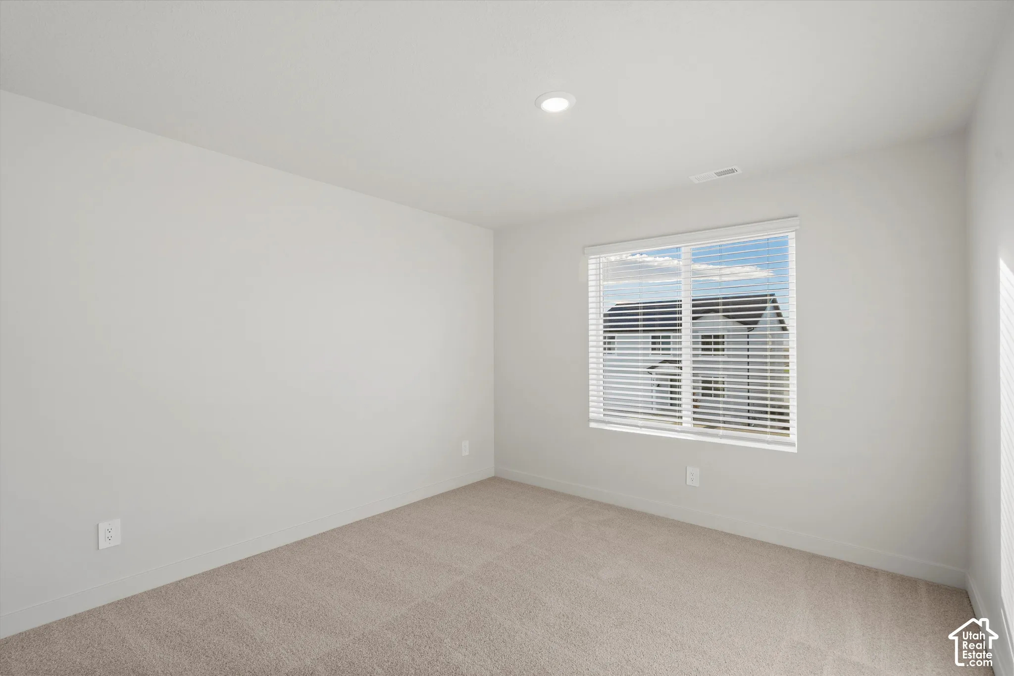 Neutral interior space featuring high-pile wall-to-wall carpeting, recessed ceiling lighting, and windows equipped with horizontal blinds