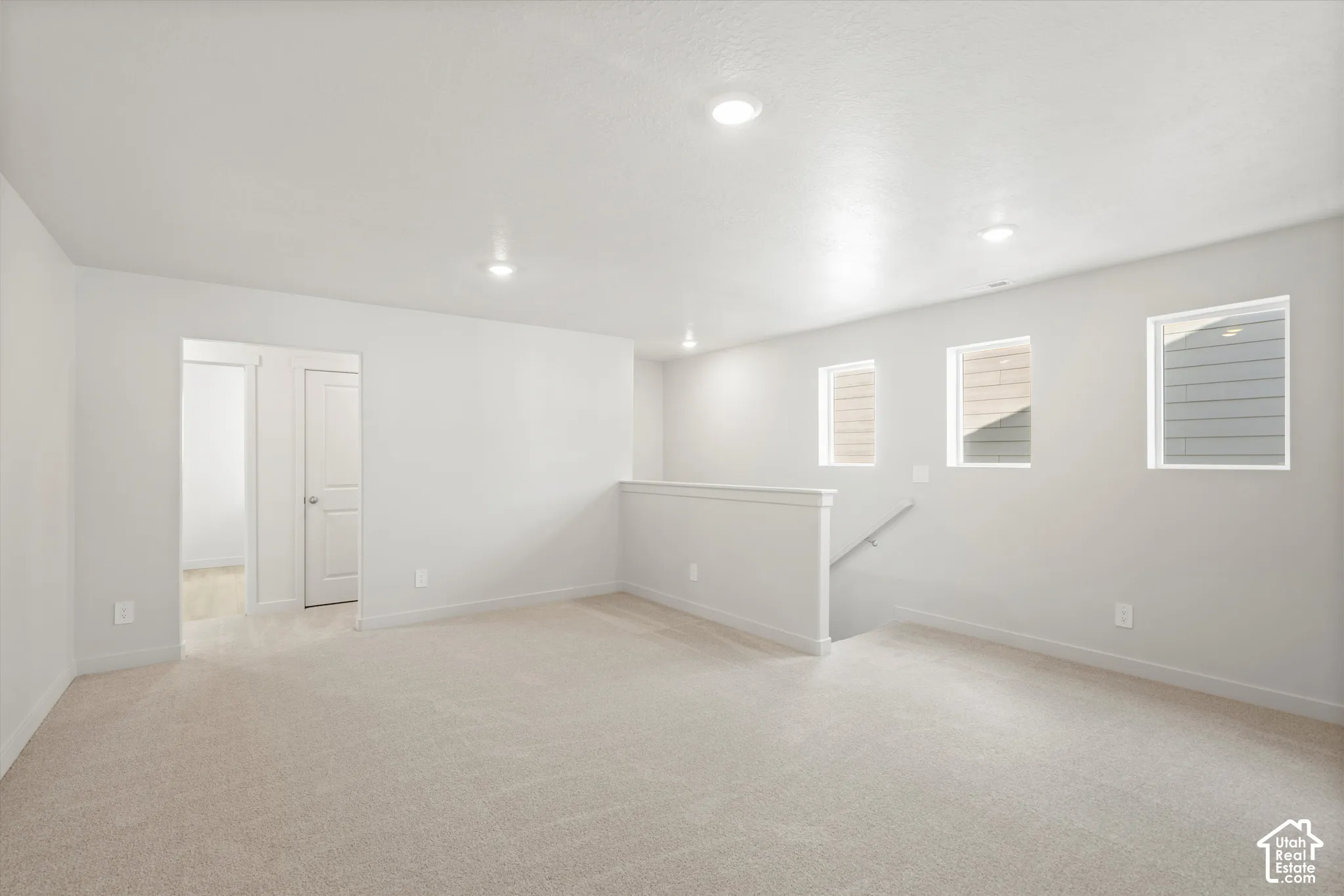 Open-concept area featuring neutral wall-to-wall carpeting, recessed ceiling lighting, and three picture windows