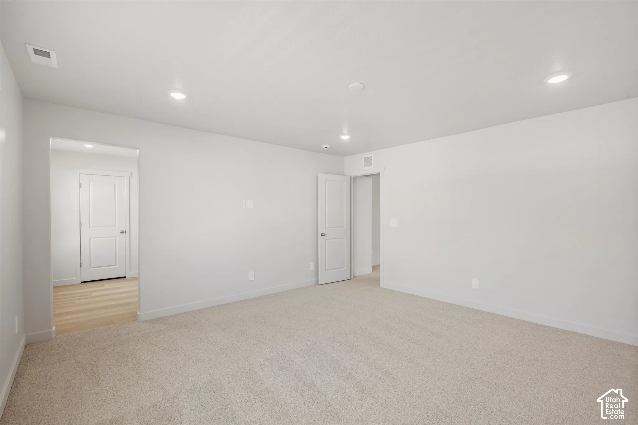 Neutral-toned carpeting, recessed ceiling lighting, and solid-core interior doors