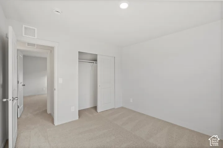 Interior room featuring neutral wall paint, wall-to-wall carpeting, recessed ceiling lighting, and a reach-in closet with sliding doors