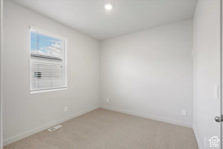 Neutral-toned walls, plush wall-to-wall carpeting, recessed ceiling lighting, and a single-pane window with adjustable horizontal blinds