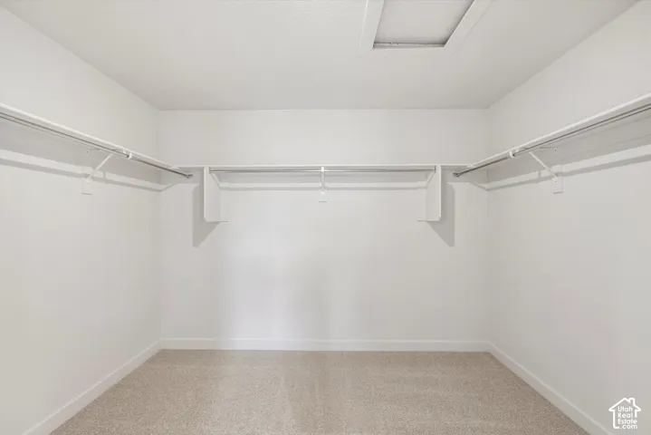 Walk-in closet featuring neutral carpeting and integrated tiered shelving with metal garment rods