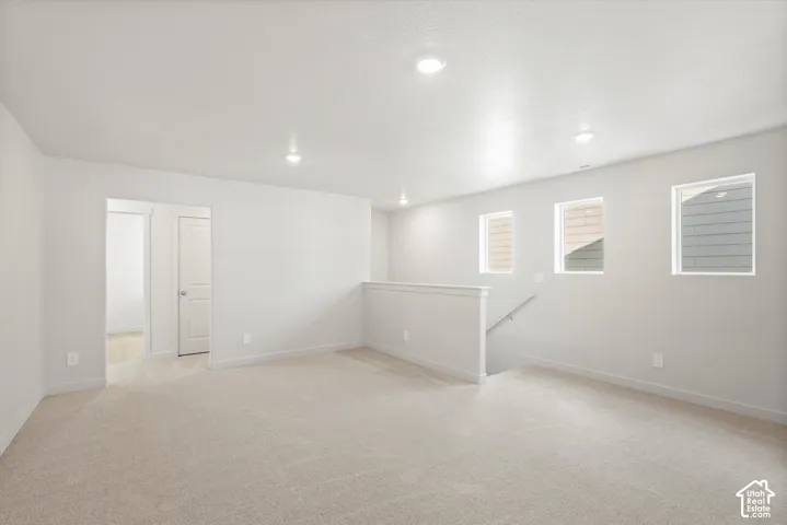 Open-concept area featuring neutral wall-to-wall carpeting, recessed ceiling lighting, and three picture windows