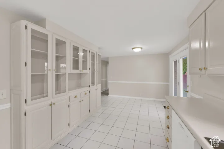 Built-in floor-to-ceiling cabinetry with glass-front display doors, ceramic tile flooring, and double-door entry