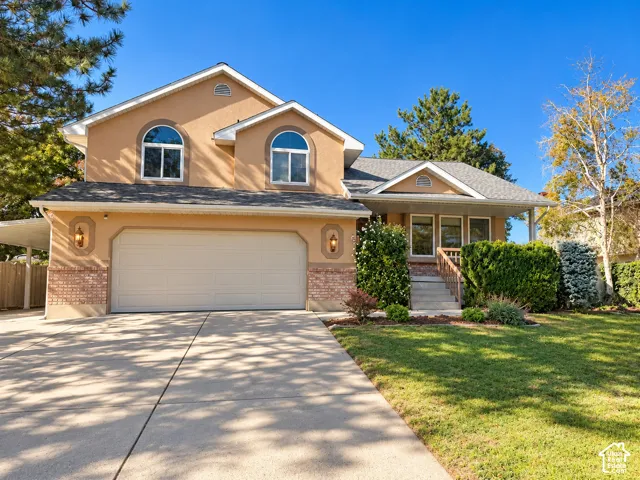 Two-story residence featuring a stucco and brick exterior, an attached two-car garage, arched windows, and a covered front entry with steps