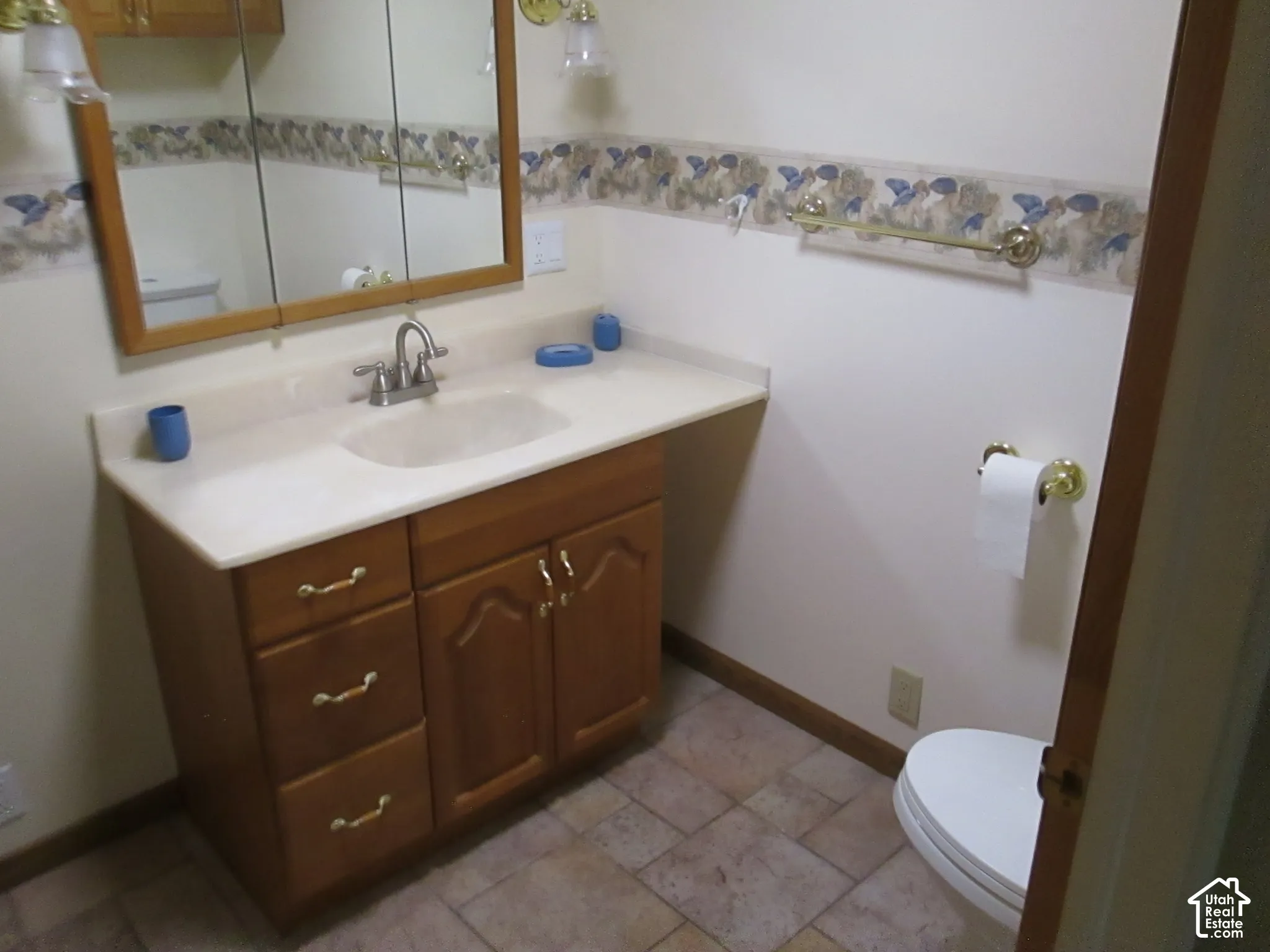 Vanity featuring wood-finish cabinetry, integrated countertop with sink, multi-drawer storage, wall-mounted medicine cabinet, and ceramic tile flooring