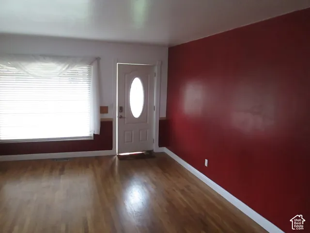 Wood-finish flooring, a solid core door with an oval glass insert, and large horizontal window with slatted blinds