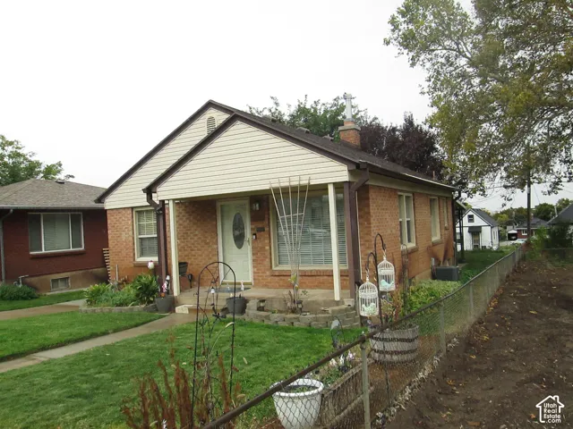 Single-story brick and siding exterior featuring a covered front porch, concrete entryway, gable roofline, and chimney