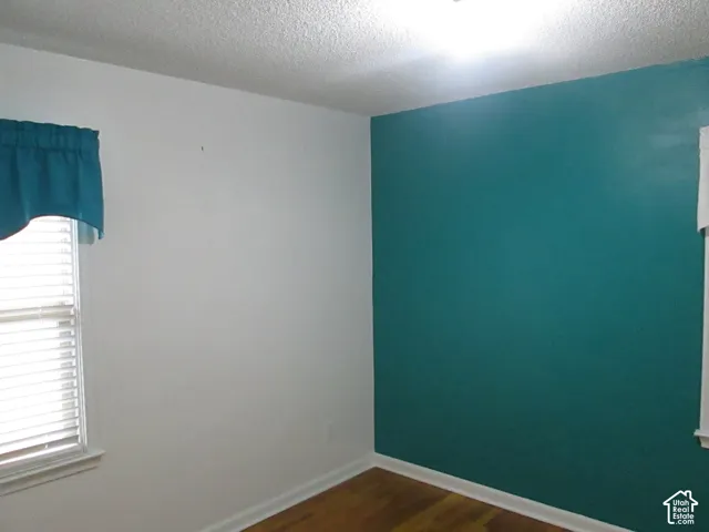 Hardwood flooring featuring an accent wall, two windows, and integrated horizontal blinds