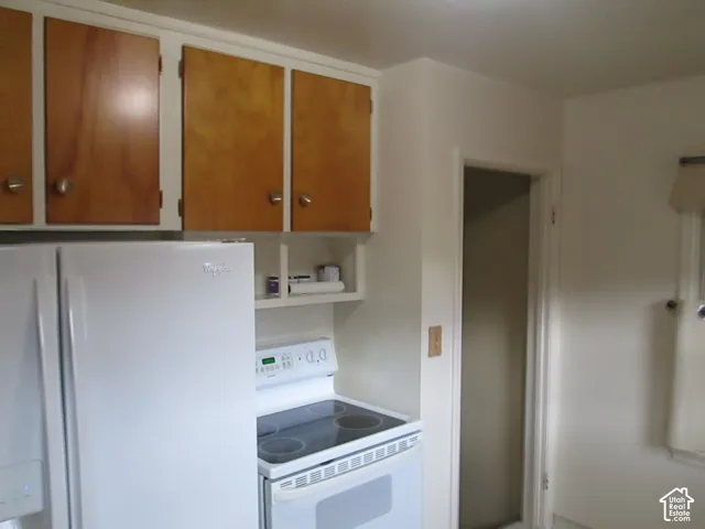 Kitchen featuring natural wood-finish cabinetry, white electric range, and white refrigerator