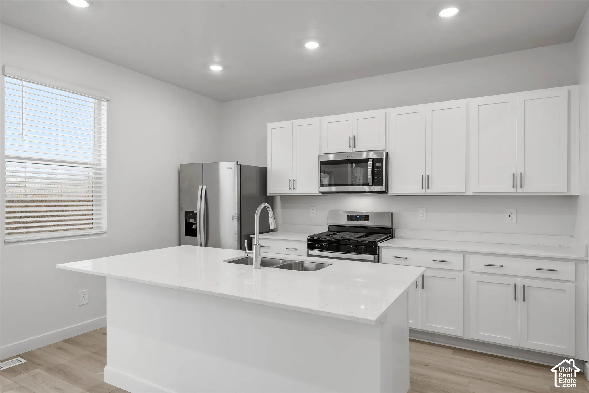 Kitchen featuring white cabinetry, quartz countertops, central island, stainless steel appliances, and recessed lighting