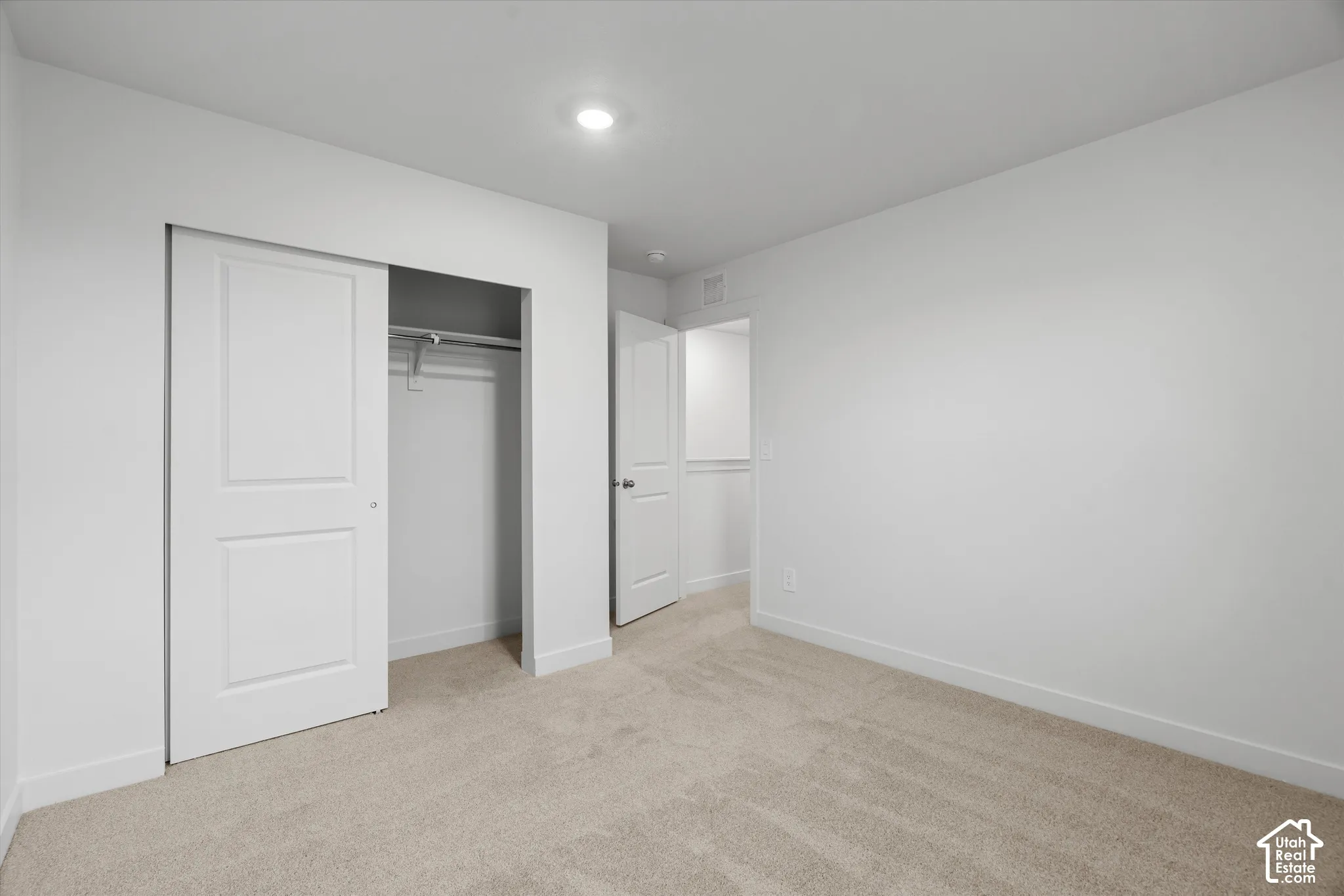 Neutral-toned wall-to-wall carpeting, recessed ceiling lighting, and a closet with a two-panel sliding door