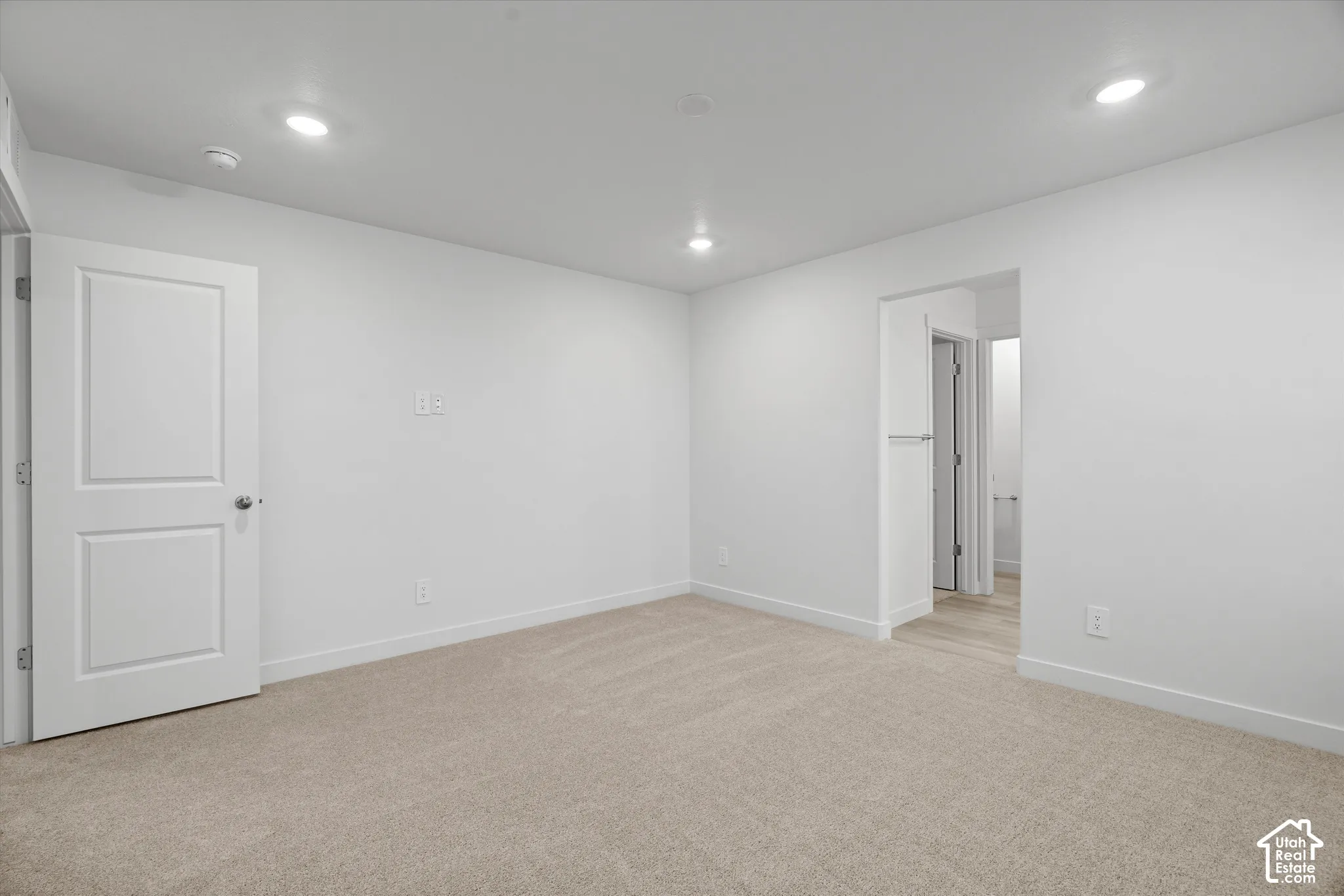 Neutral-toned carpet, recessed lighting, and a solid-core paneled door