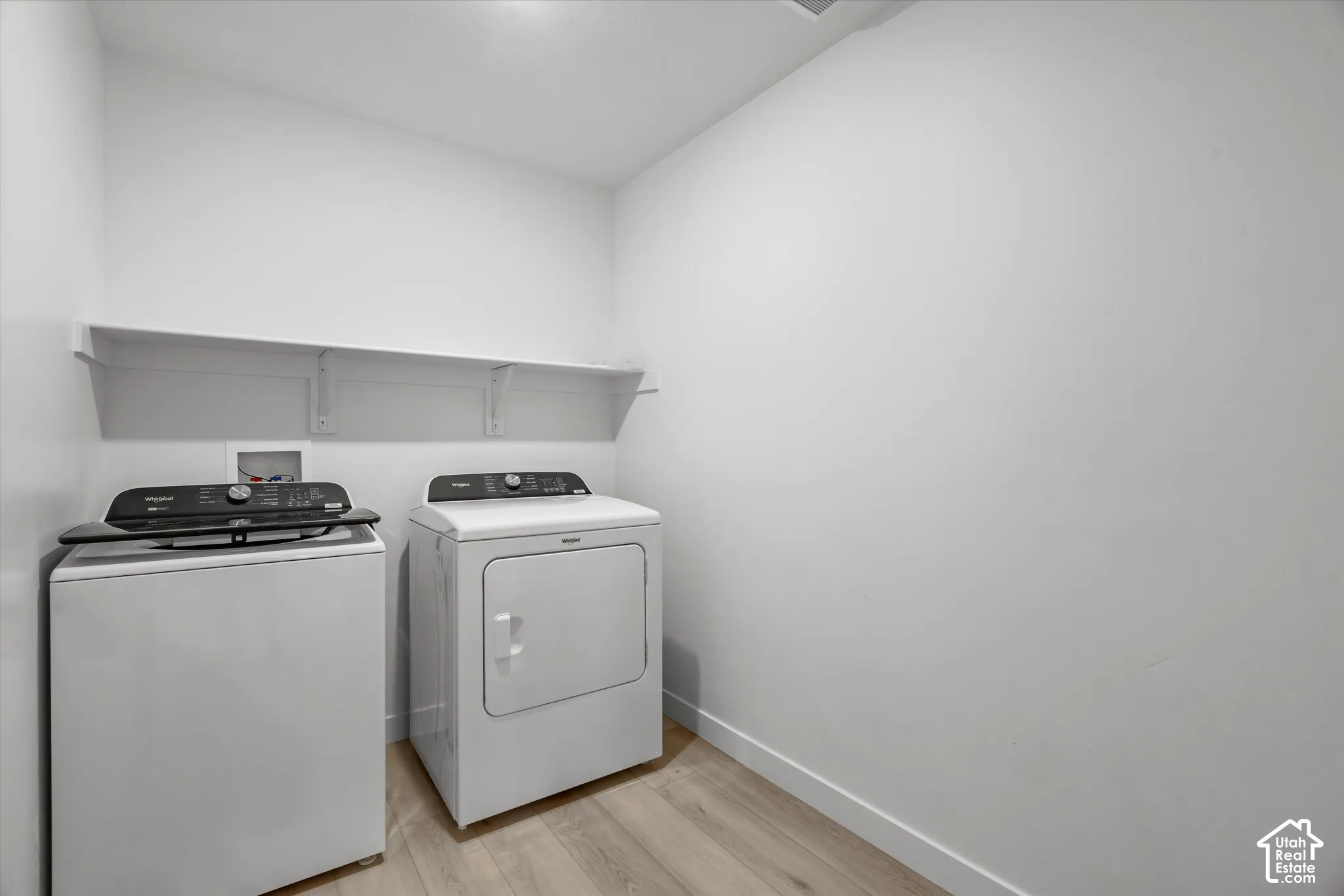 Utility area featuring wood-finish flooring and a white built-in wall shelf