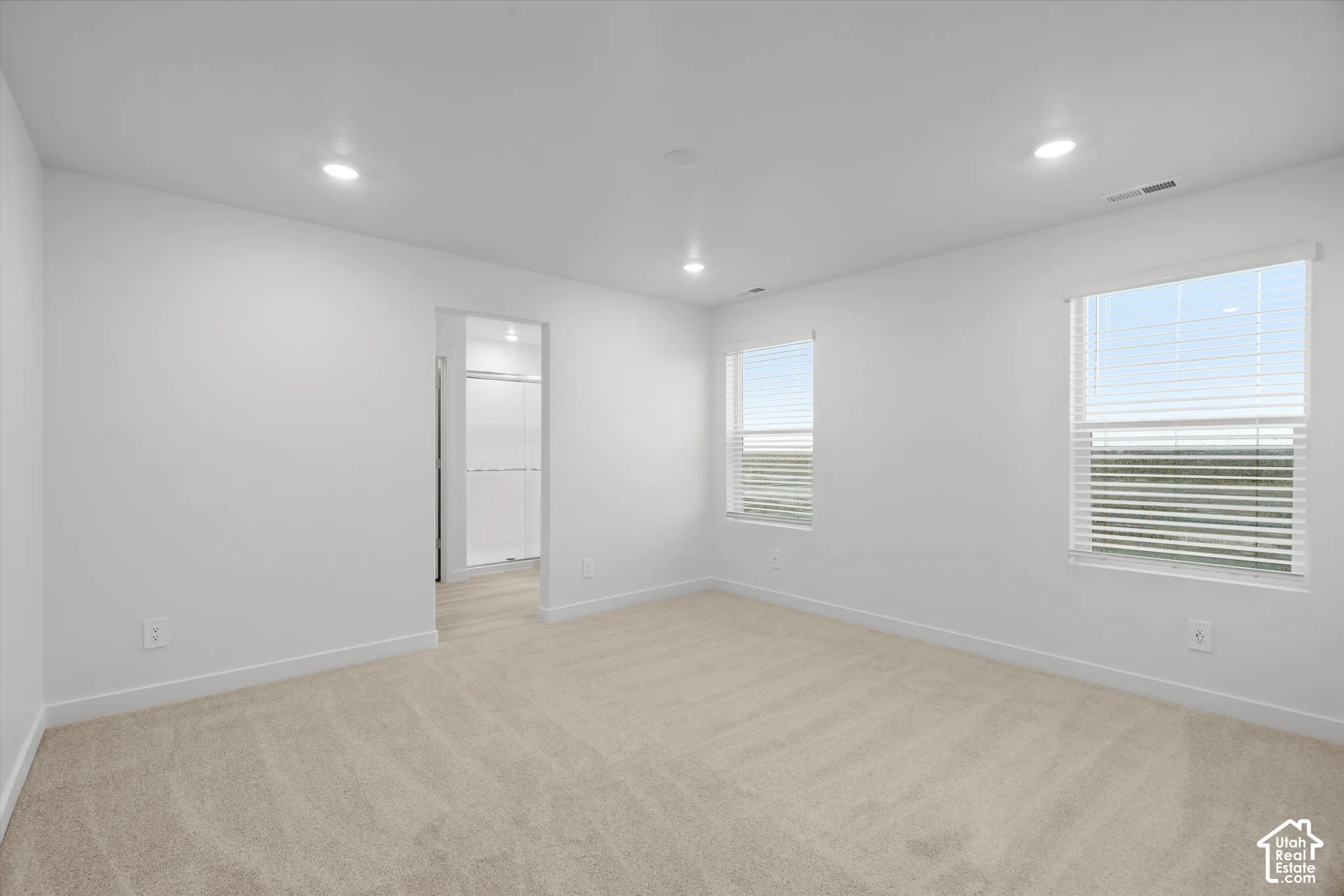 Neutral-toned carpeted flooring, recessed lighting, and dual windows with horizontal blinds