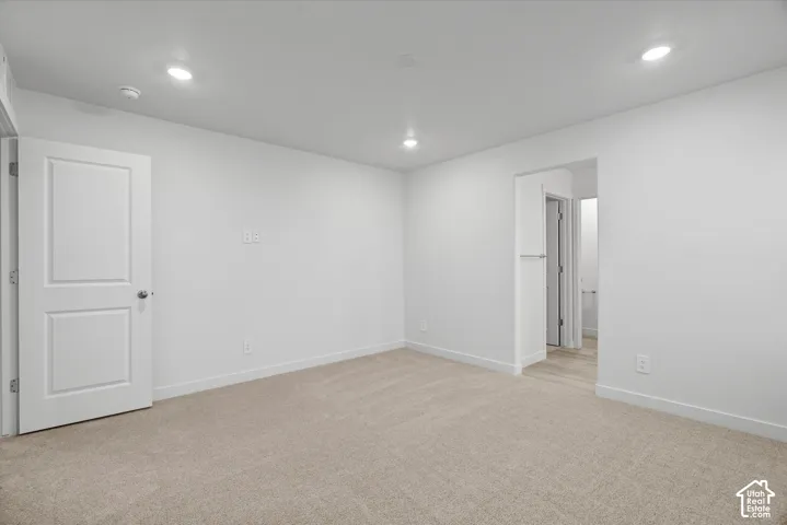 Neutral-toned carpet, recessed lighting, and a solid-core paneled door
