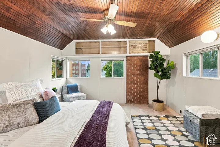 Bedroom with cool wood ceiling, exposed brick, and windows on three sides.