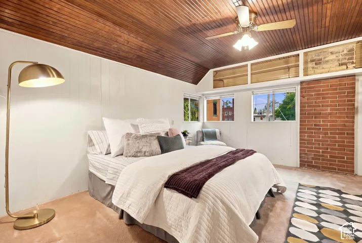 Bedroom with cool wood ceiling, exposed brick, and lots of windows.