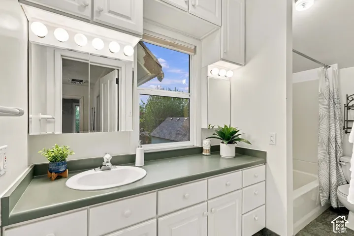 Full bathroom on the second level with tub and shower, toilet, sink, and large vanity area with cabinets and a window.