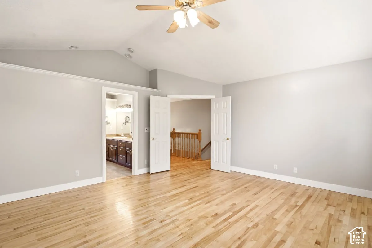 Vaulted ceilings, wood-finish flooring, recessed lighting, and a ceiling fan with integrated light fixture