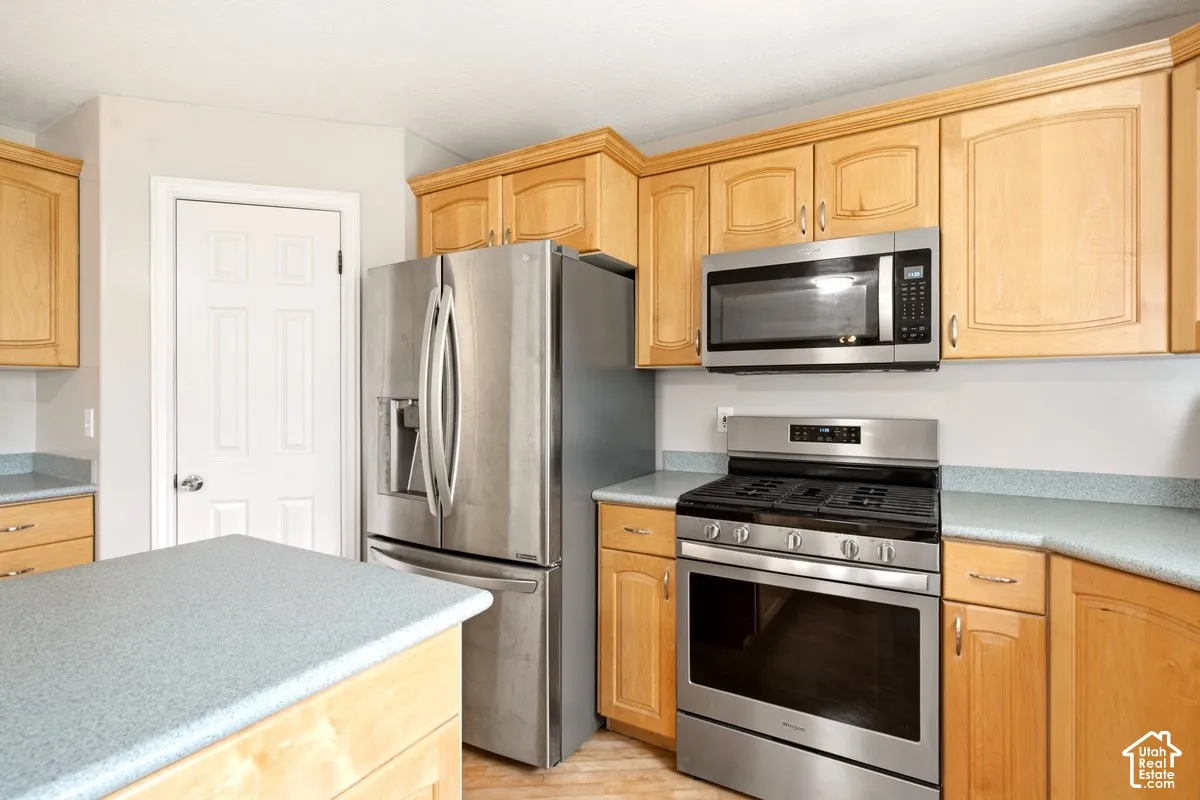Kitchen featuring wood cabinetry, stainless steel appliances, a gas range with an over-the-range microwave, and solid-surface countertops