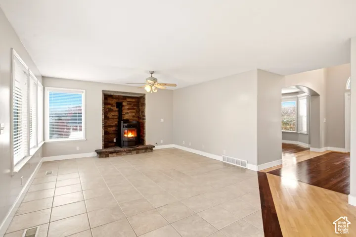 Living area featuring neutral tile flooring, stone-accented fireplace surround, arched entryway, and wood-finish flooring