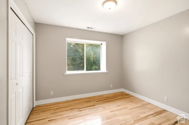 Neutral-toned walls paired with natural wood-finish flooring, a double-panel closet door, and a single-pane sliding window