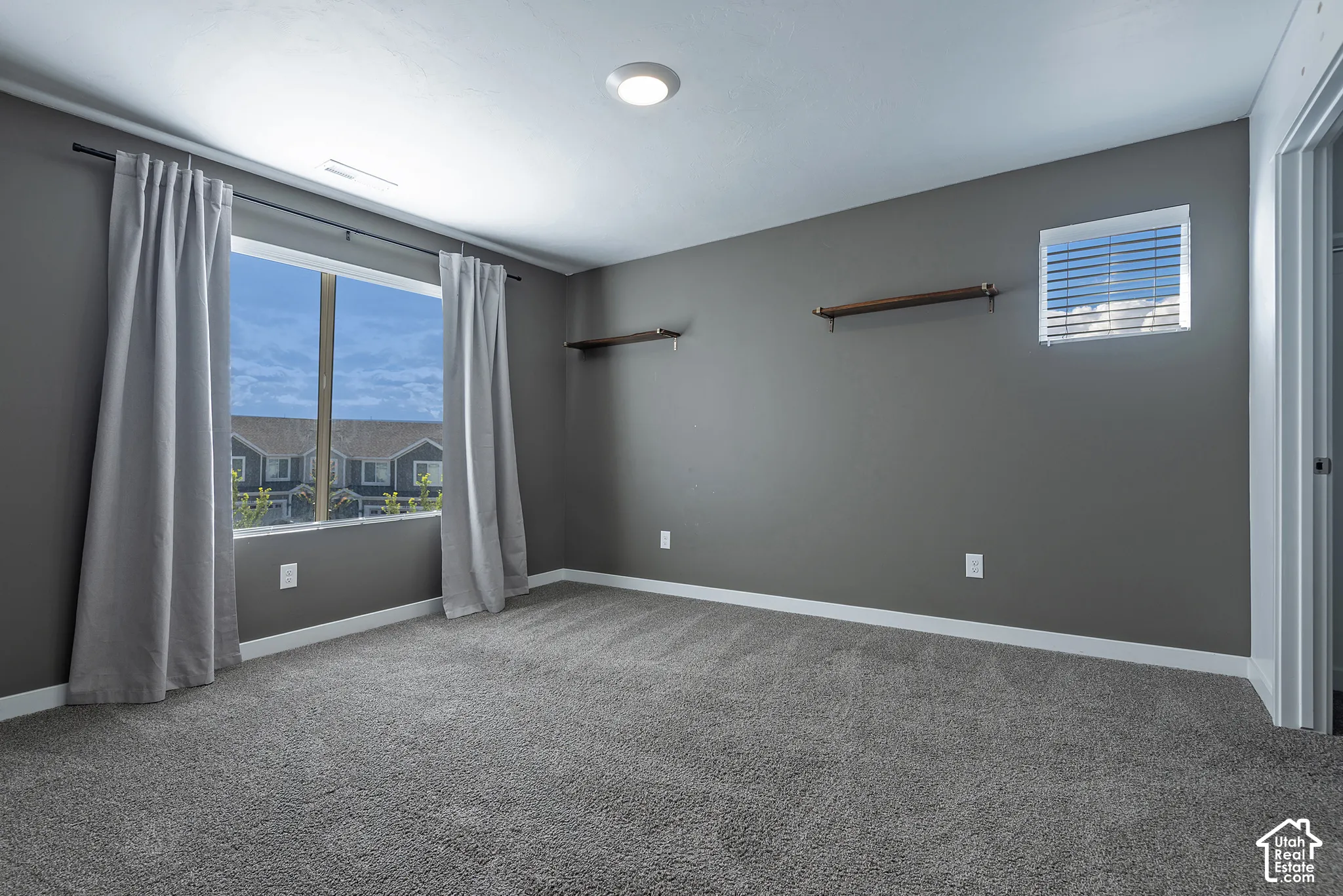Neutral-toned walls, wall-to-wall carpeting, dual-pane windows, and built-in wall shelving
