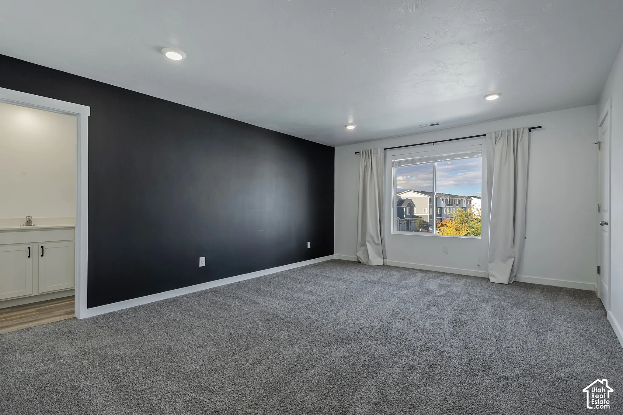 Interior space featuring a dark accent wall, plush carpeting, recessed lighting, and a window with exterior scenery