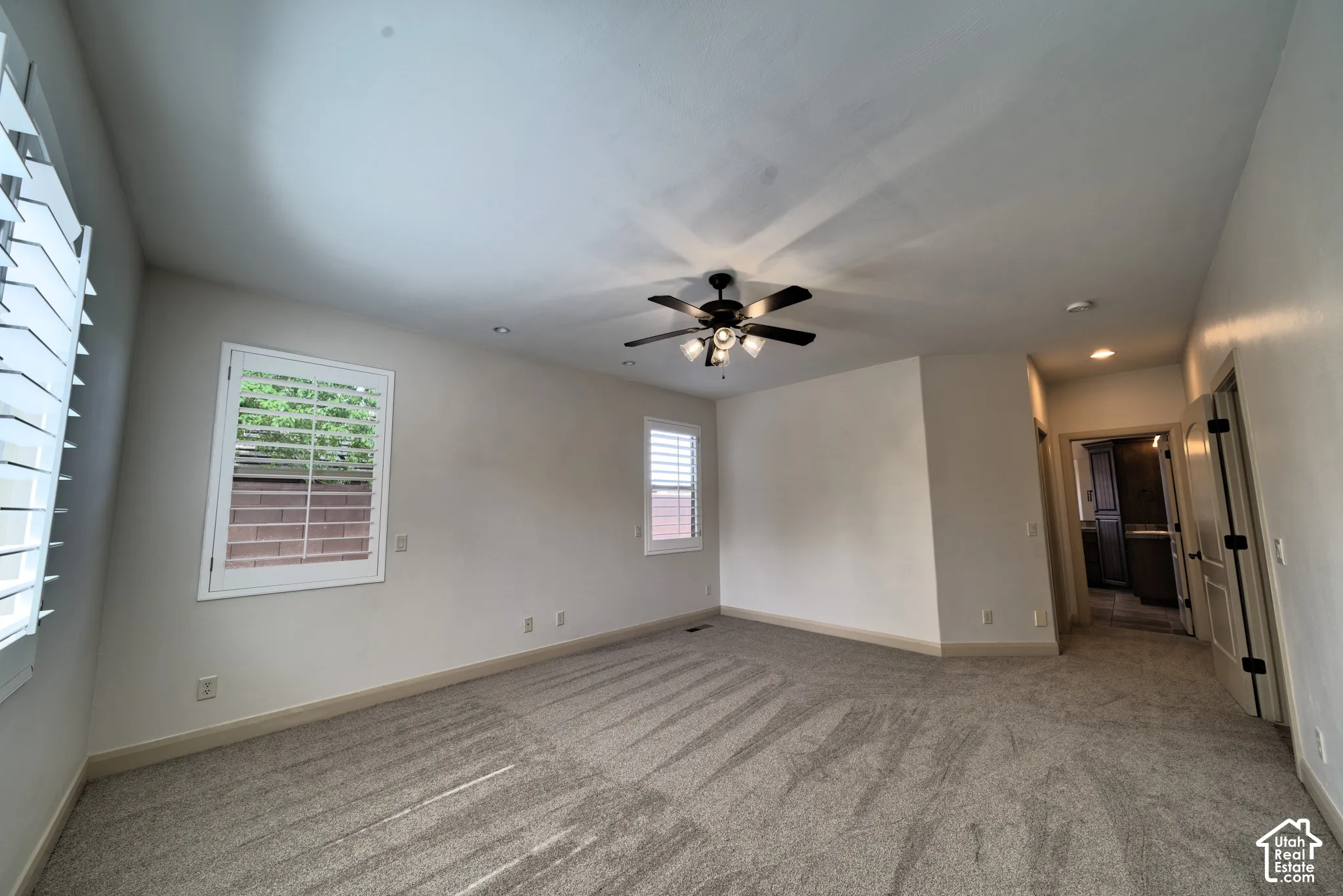 Main-floor primary bedroom with new carpet, plantation shutters and a ceiling fan.