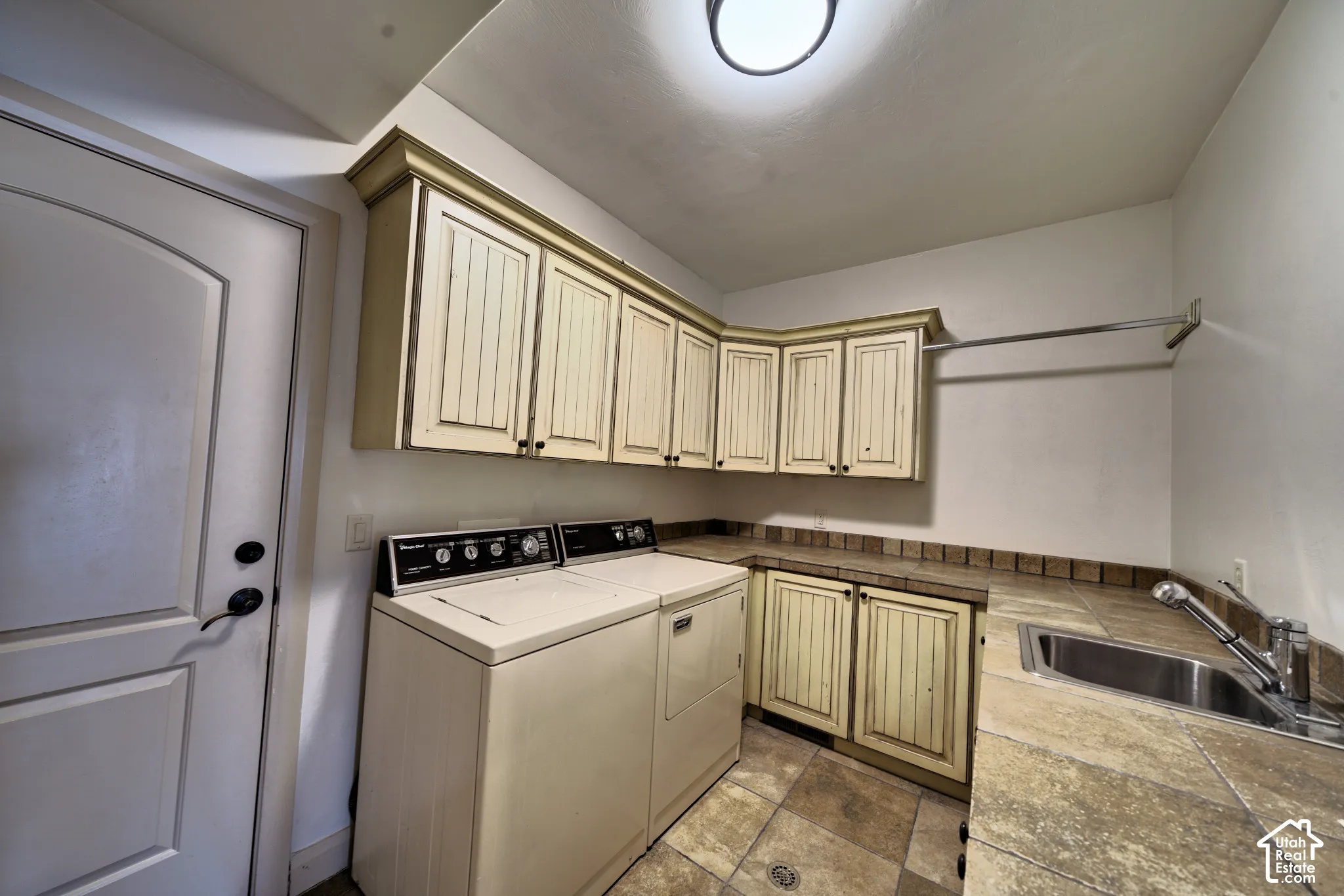 Laundry room with cabinets, a counter and a utility sink.