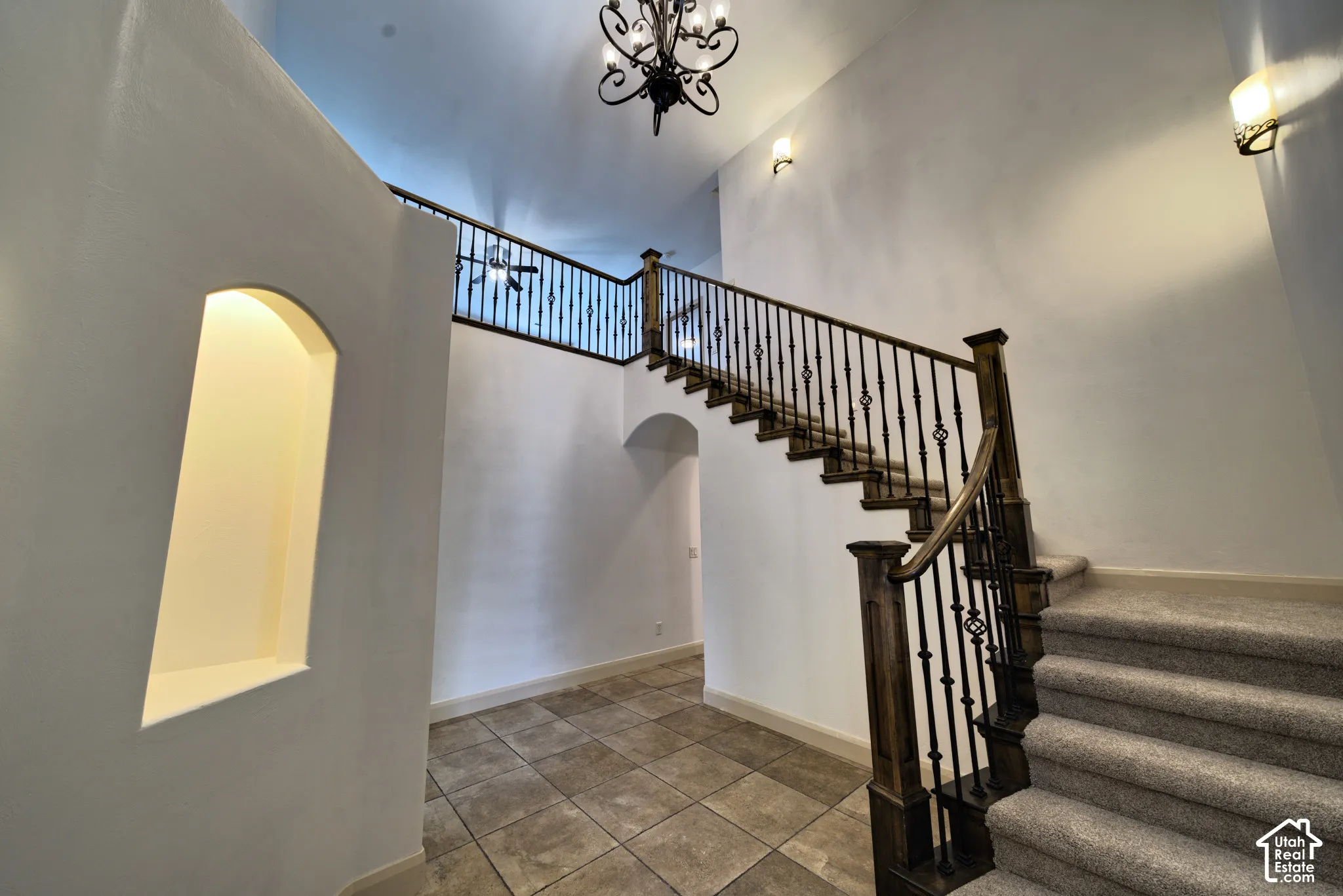 Two-story entry with a lighted arched wall nook and an iron-rail staircase.