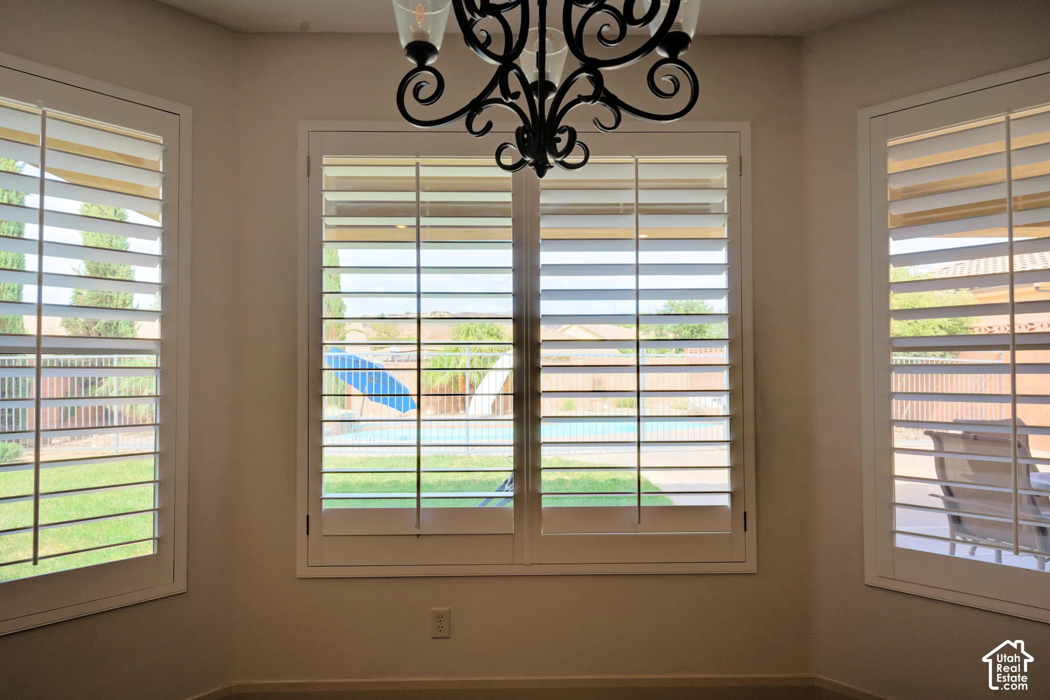 Bay-window eating area with plantation shutters, looking out at the pool.