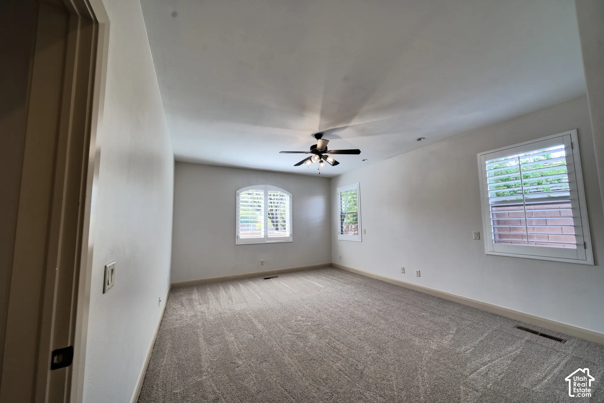Primary bedroom with an arched window and plantation shutters.