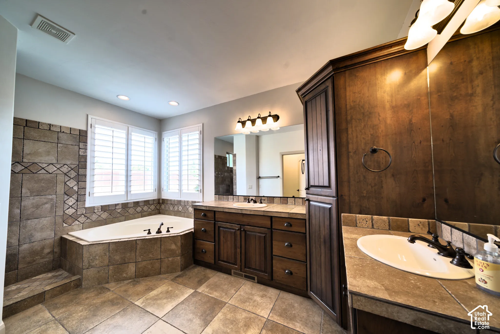 Primary bathroom with a corner jetted tub and two separate vanities.