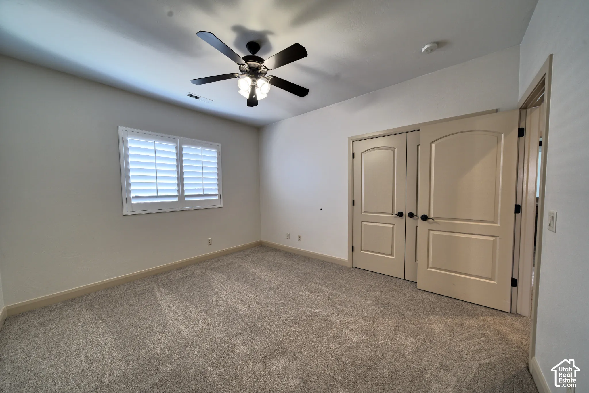 Upstairs bedroom with plantation shutters and a ceiling fan.