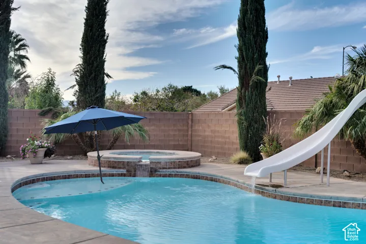 Pool with a slide, a shallow lounging ledge and the spa spilling over into it.