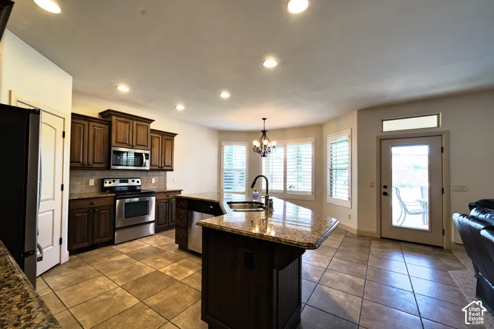 Stainless steel appliances, stone tile backsplash and a door out to the covered patio.