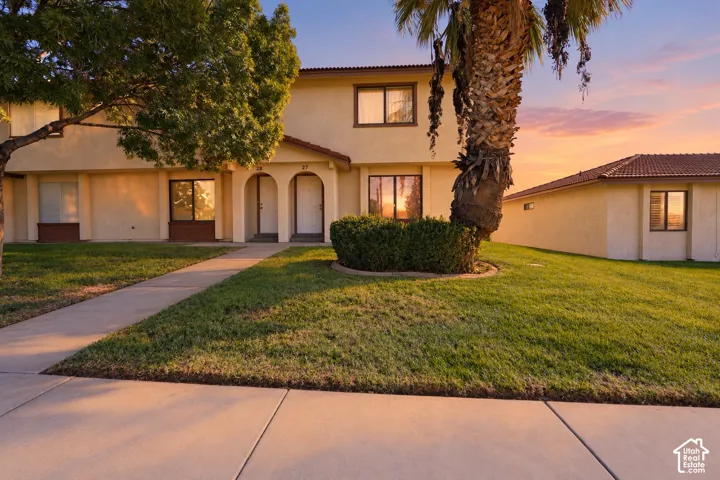 Stucco exterior featuring dual arched entryways, concrete tile roofing, and a concrete walkway