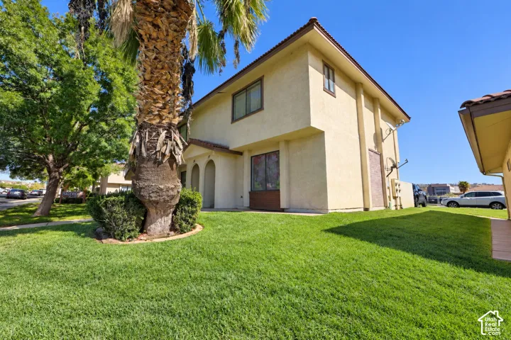 Two-story stucco exterior featuring arched entryway detailing, a tile roof, and manicured landscaping with a mature palm tree
