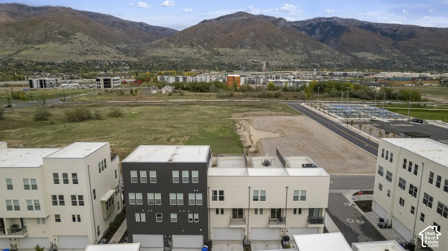 Multi-story residential structures featuring contemporary flat-roof architecture, exterior balconies, and attached garage entries, set against a backdrop of prominent mountain terrain