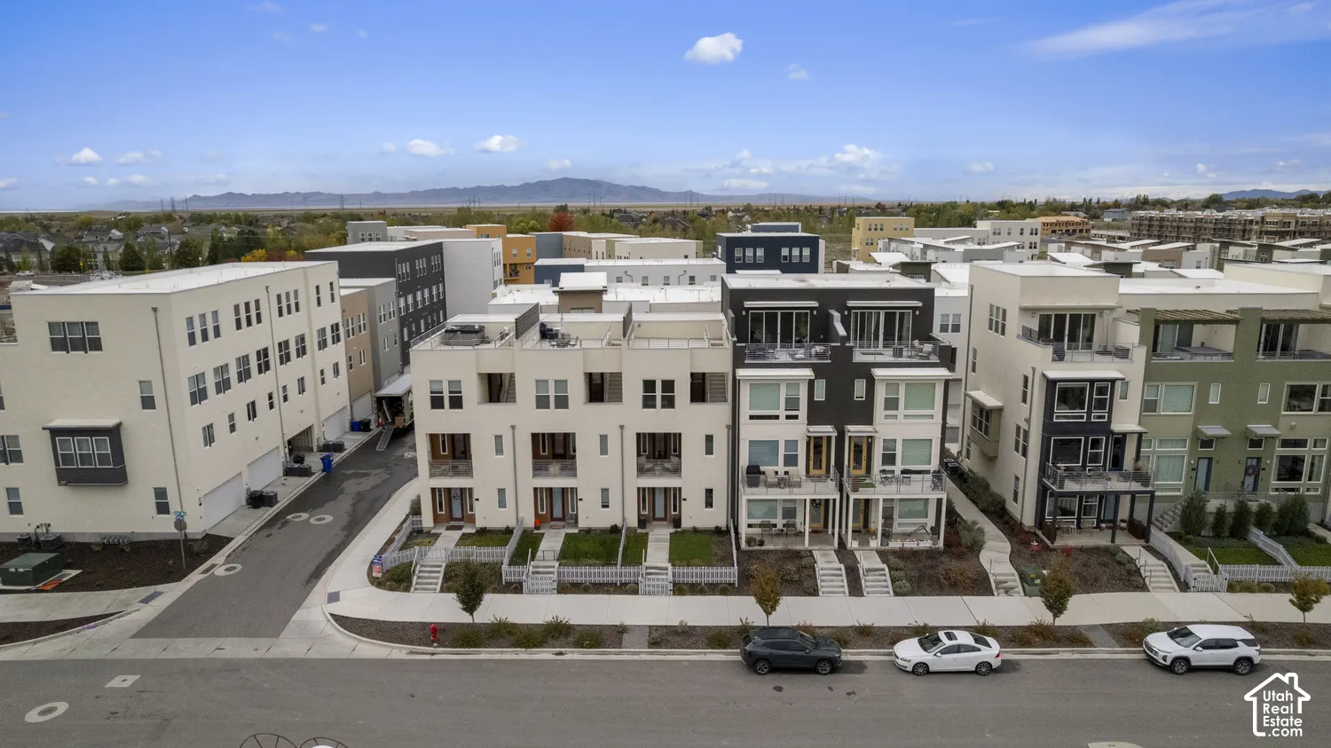 Multi-level townhome architecture featuring contemporary facades, private balconies, expansive windows, concrete-paved walkways, and mountain scenery