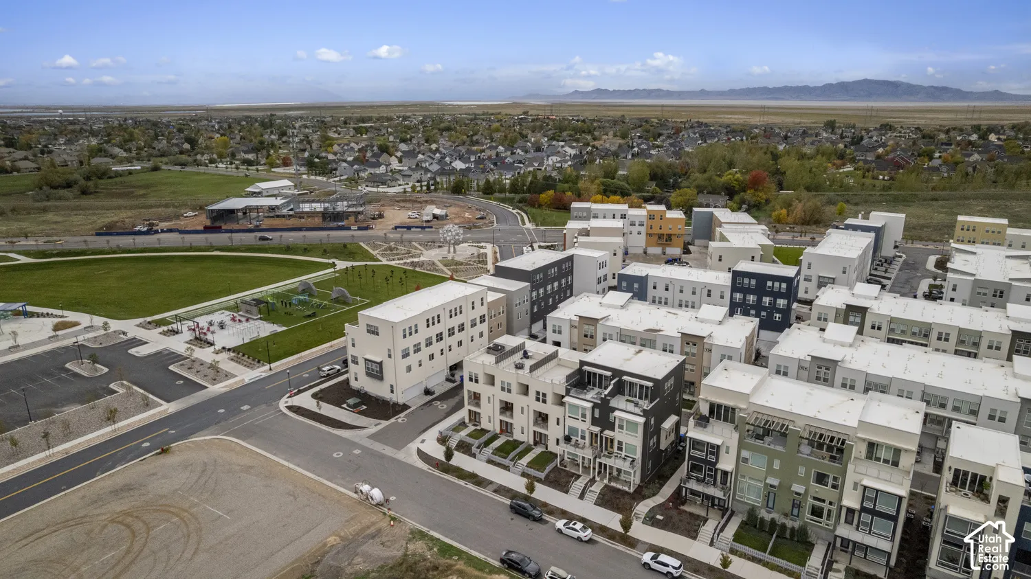 Aerial perspective of a multi-level residential development featuring contemporary architectural styling, integrated private balconies, attached garages, landscaped street-level grounds, and mountain range backdrop