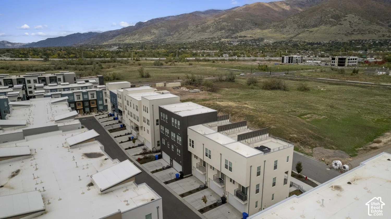 Modern multi-level townhome architecture featuring flat rooflines, private balconies, attached garages, and a prominent mountain backdrop