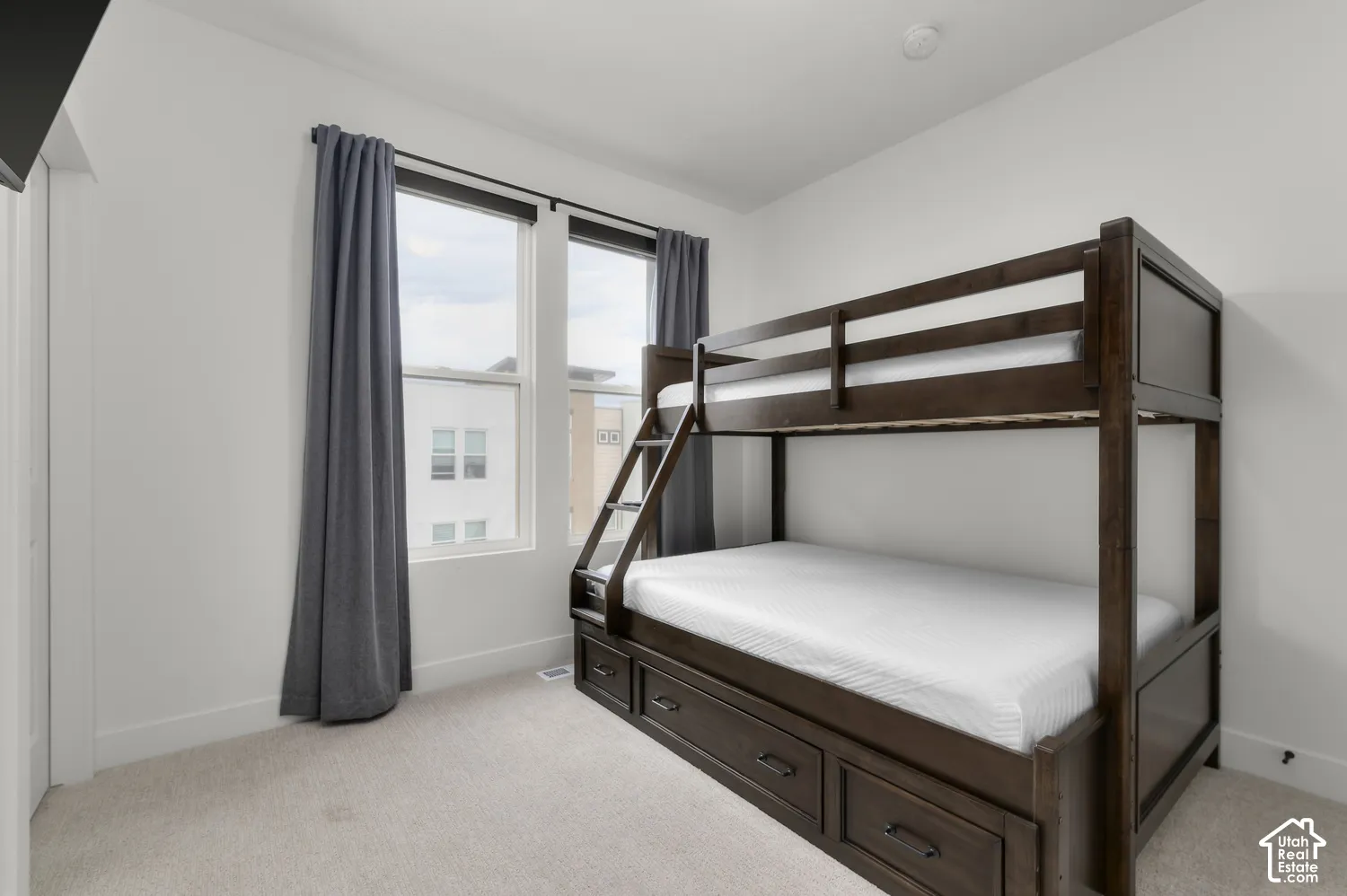 Neutral wall finishes, plush carpeting, and tall windows featuring dark-framed casings
