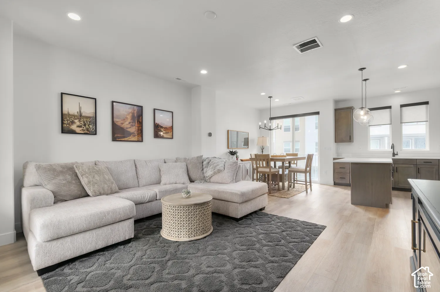 Open-concept living space featuring wood-finish flooring, recessed lighting, neutral wall color, and a kitchen island with pendant lighting